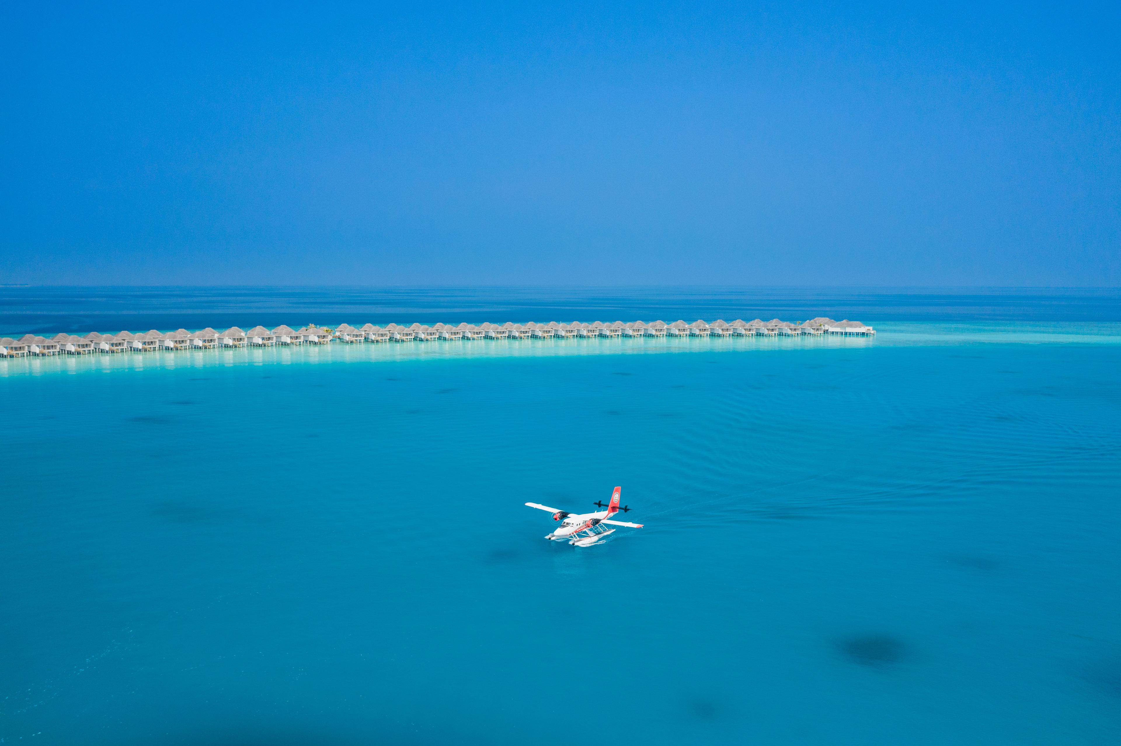 aerial view of a seaplane in the Maldives with overwater villas behind