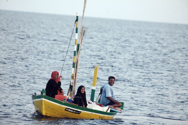 maldivian man and two woman travelling on a traditional small boat